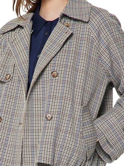 Detalle del estampado de cuadros, botones y cuello de gabardina corta tipo globo.